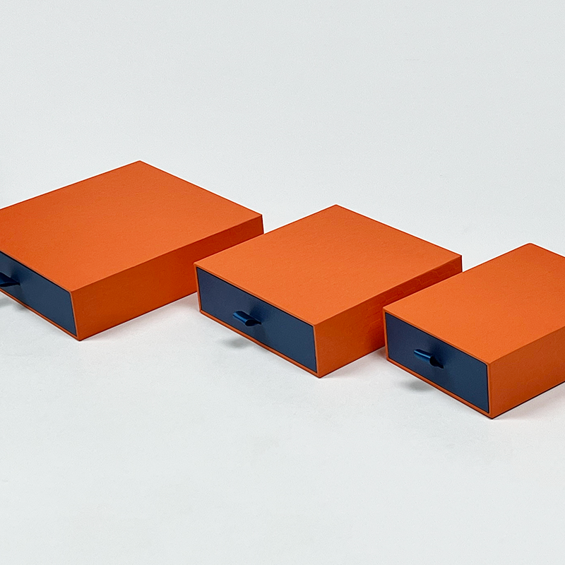 Three orange and navy sliding drawer gift boxes in different sizes
