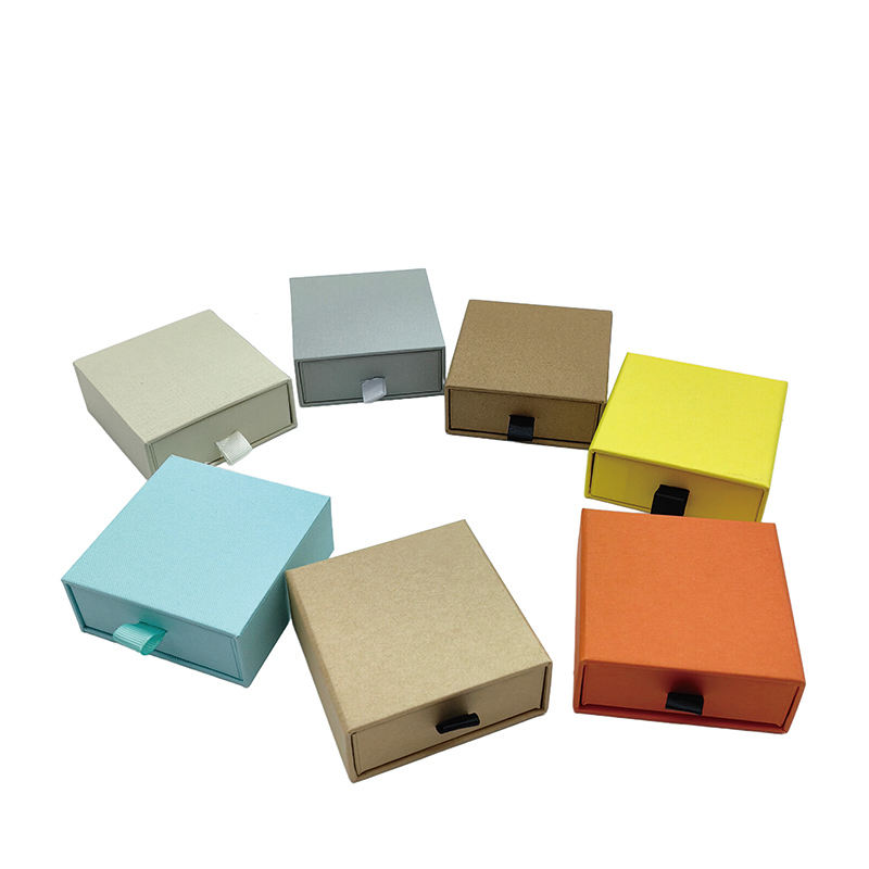 Seven small paper drawer boxes in different colors with ribbon pulls