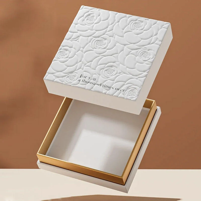Cream lift-off lid gift box with a raised floral pattern and gold-edged base