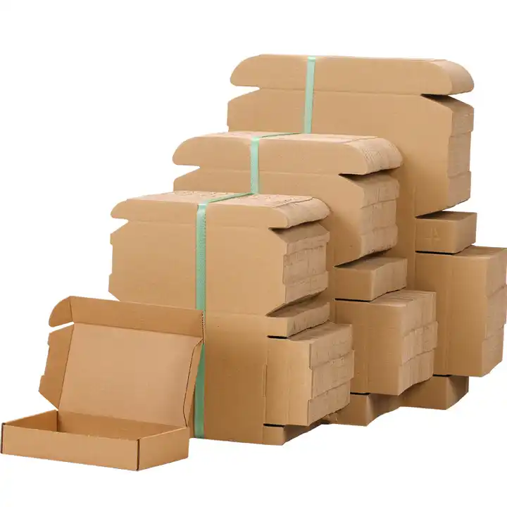 Stacks of flat kraft corrugated mailer blanks beside an assembled box